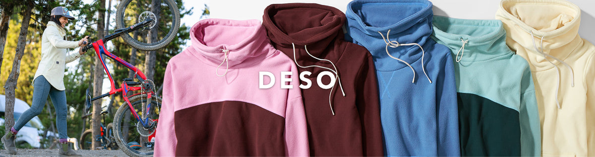 Four color-blocked hoodies by DESO are shown in a row, with a person riding a pink bicycle in the background. The hoodies are in pink, dark brown, blue, mint green, and cream.