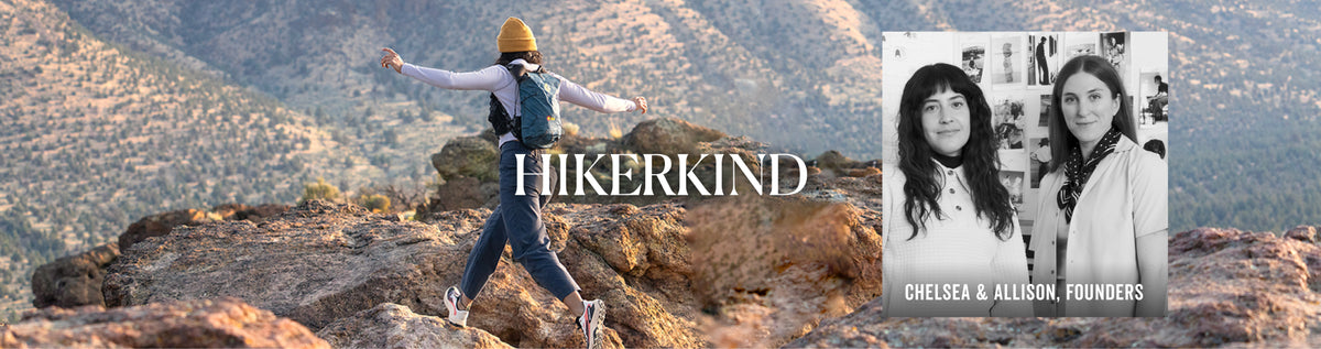 A scenic outdoor photo of a person hiking on a rocky mountain ridge with hills in the background, overlaid with the text 'HIKERKIND' and a black-and-white inset photo of two women labeled 'CHELSEA & ALLISON, FOUNDERS'.