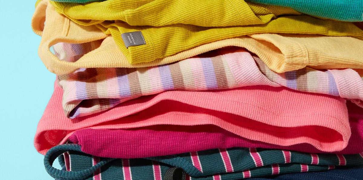Stack of colorful folded headlands ribbed tops on a light blue background.