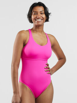 Happy wet girl in one-piece swimwear posing against sea Stock